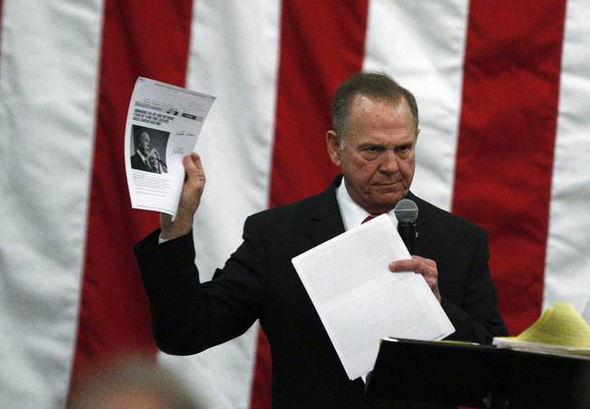 U.S. Senate candidate Roy Moore holds up pages with a news story about himself as he speaks at a campaign rally, Monday, Dec. 11, 2017, in Midland City, Ala.