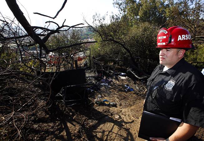 Los Angeles Fire Department Fire Arson Counter-Terrorism investigator Angel Alvarez checks a burned out homeless camp after a brush fire erupted in hills in Elysian Park in Los Angeles Thursday, Dec. 14, 2017. The National Weather Service said extreme fire danger conditions could last through the weekend due to lack of moisture along with a likely increase in wind speeds. 