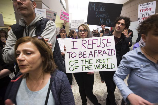 Holly Smith, center, of Las Vegas holds a sign during a rally protesting President Trump's immigration order at McCarran International Airport in Las Vegas Sunday, Jan. 29, 2017.
