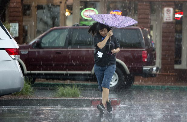 A woman runs to her car in a parking lot at Sunset Road and Green Valley Parkway as a fast moving thunderstorm passes over Henderson Monday, April 3, 2017.