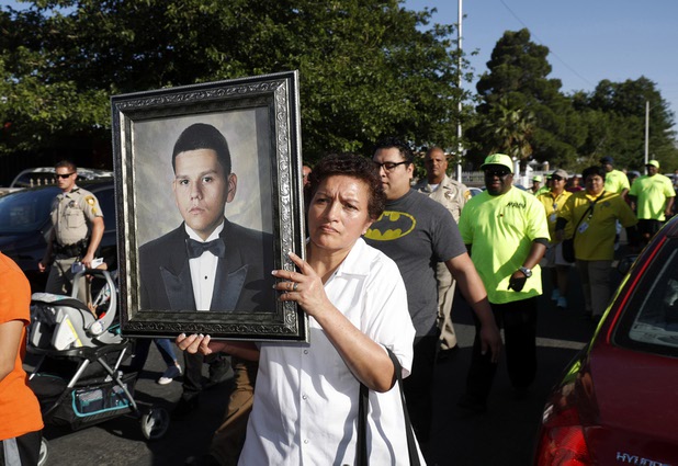 A family friend holds a portrait of slain teen Jose de Jesus Alatorre Guzman during a march and vigil in a neighborhood near Decatur Boulevard and Bonanza Road Monday, May 15, 2017. Alatorre Guzman, 19, was shot and killed in a drive-by shooting on May 11, 2016. The case is yet unsolved.