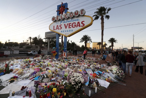 The "Welcome to Las Vegas" sign is surrounded by flowers and items, left after the Oct. 1 mass shooting, in Las Vegas Monday, Oct. 9, 2017.