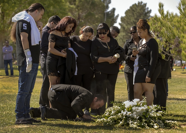 A family member blows away the dust about the newly-filled plot during a burial service for Erick Silva, 21, commencing from the Davis Memorial Park on Thursday, October 11, 2017. Silva was killed in the October 1st mass shooting while working his security job near the stage at Route 91 Harvest festival.