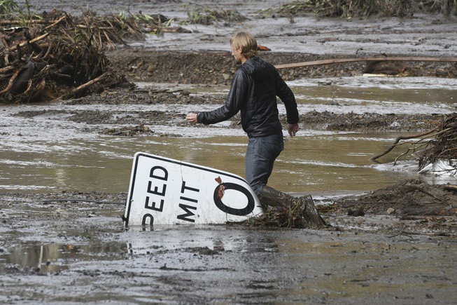 Phillip Harnsberger crosses through mud from a flooded creek on ...