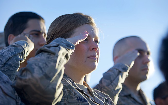 Airmen salute during the singing of the national anthem before ...