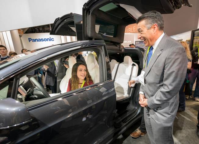 Nevada Governor Brian Sandoval, right, reacts to the sight of his teenage daughter Marisa Sandoval behind the wheel of a Tesla Model X sport utility vehicle in the Panasonic booth at CES in the Las Vegas Convention Center on Thursday, Jan. 11, 2018. CREDIT: Mark Damon/Las Vegas News Bureau