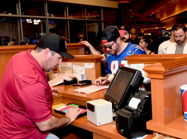 Fans flock to the South Point for the big game. In this photo, Brendan Gaughan, NASCAR driver and son of hotel owner Michael Gaughan, takes a bet at the South Point Sportsbook window for a New England Patriot fan. Sunday, February 4, 2018. 