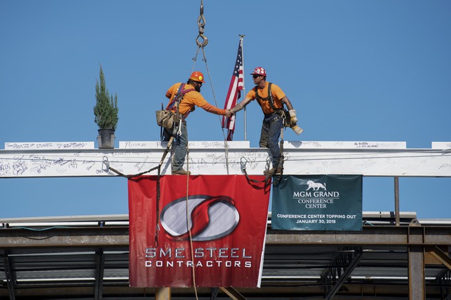 Iron workers shake hands after securing the final beam during ...