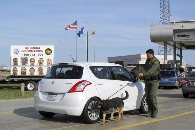 A Border Patrol agent uses a dog to inspect a car waiting to pass through the Laredo North vehicle checkpoint in Laredo, Texas, on Feb. 2. The dogs are trained to catch drugs and people who try to enter the U.S. illegally in trunks and vehicle compartments. 
