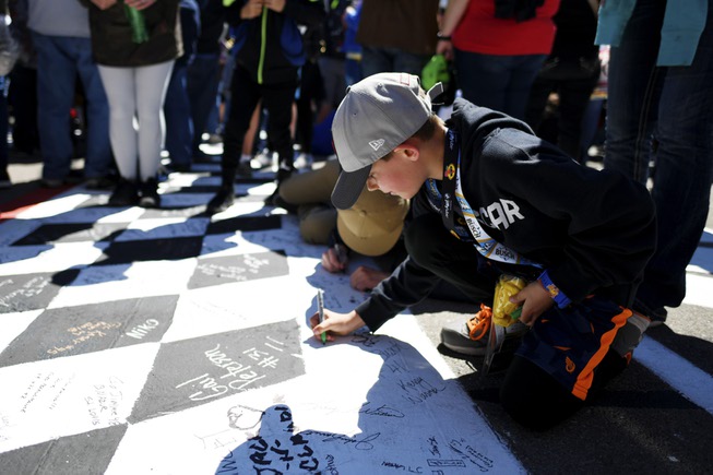 A young fan signs the start finish line before the ...