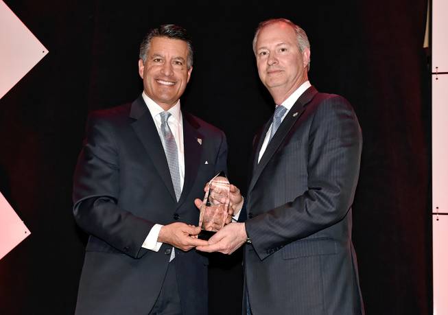 Nev. Gov. Brian Sandoval, left, presents Steve Hill, president and chief operating officer of the LVCVA and chairman of the Las Vegas Stadium Authority with the Caesars Community Hero award during Caesars Entertainment Community Review reception at the Rio All-Suites Hotel & Casino Monday, March 5, 2018, in Las Vegas.