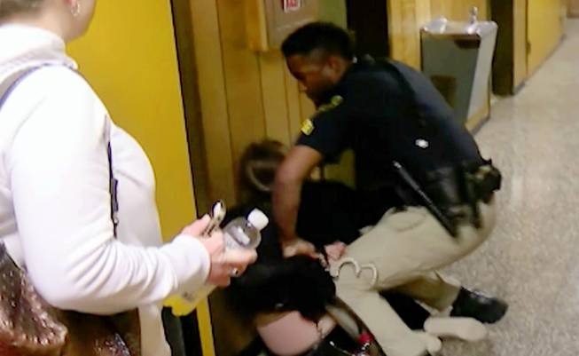 In this Monday, Jan. 8, 2018, file image made from video, middle-school English teacher Deyshia Hargrave is handcuffed by a city marshal after complying with a marshal's orders to leave a Vermilion Parish School Board meeting in Abbeville, La., west of New Orleans. Louisiana’s attorney general sued a local school board Thursday, March 8, 2018, over a meeting disrupted by the video-recorded arrest of Hargrave being roughly handcuffed on a hallway floor after she criticized the district superintendent’s pay raise. 