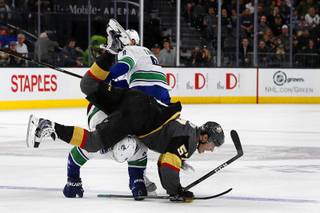 Golden Knights left wing David Perron (57) falls over Vancouver Canucks left wing Brendan Leipsic (9) during the second period of their NHL game at T-Mobile Arena Tuesday, March 20, 2017.
