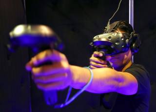 Cliff Cabiles shoots a virtual arrow during an archery game at the Virtual Reality Zone at the Orleans Friday, March 23, 2018.