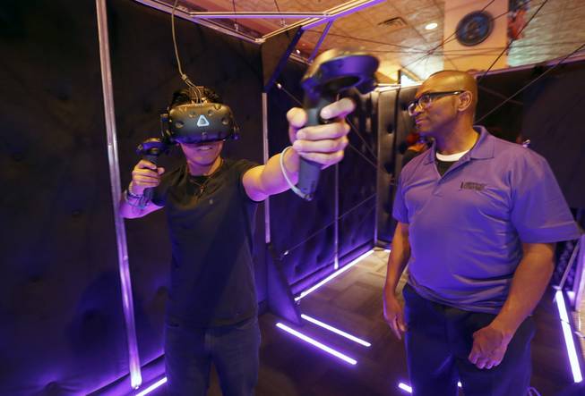 Cliff Cabiles tries out a virtual bow and arrow as VR guide Ken Harmon looks on at the Virtual Reality Zone at the Orleans Friday, March 23, 2018. STEVE MARCUS