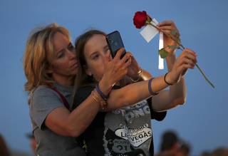 Kenzy Smith, 14, holds a rose for her mother Mynda Smith to photograph during a vigil, marking the six-month anniversary of the Oct. 1 mass shooting, near the Las Vegas Festival Grounds Sunday, April 1, 2018. Mynda's sister Neysa Tonks was one of the 58 victims of the shooting.