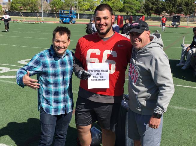 Magician Farrell Dillon, left, from the Masters of Illusion show at Bally’s helped UNLV football coach Tony Sanchez, right, present defensive lineman Ammir Aziz a scholarship after practice on Friday, April 13, 2018.