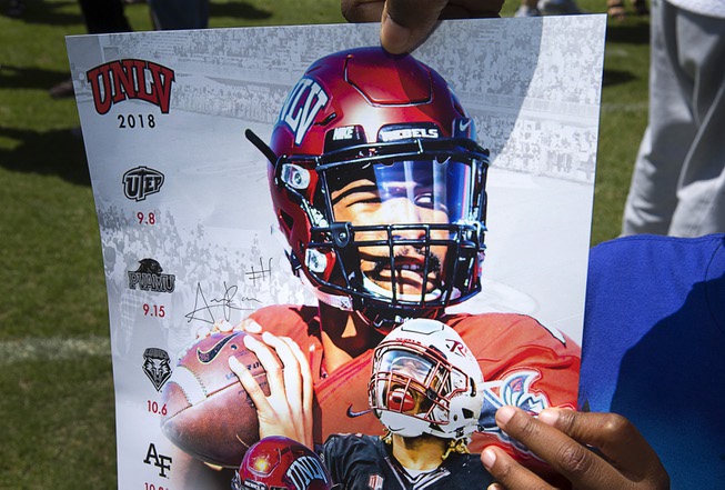 A boys shows off a poster autographed by quarterback Armani ...