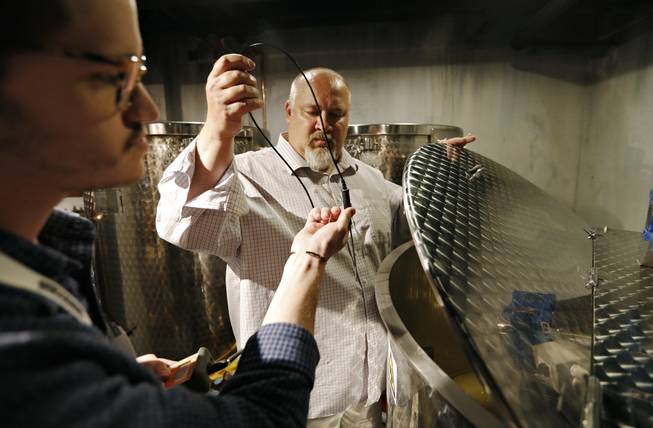 In this April 12, 2018, photo, distillery technician Cole Miller, left, and master distiller in residence George Racz check the temperature of a batch of moonshine cooking in the Mob Museum in Las Vegas. For years the museum has showcased the area's storied past in organized crime, but visitors can now also enjoy a speakeasy, a use of deadly force training experience, and an interactive crime lab exhibit. 