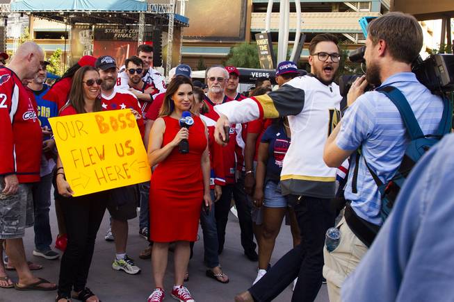 A Golden Knights fan walks in front of an ABC channel 7 camera while they interview Capitals fans during pregame festivities for Game 5 of the NHL Stanley Cup Final with the Vegas Golden Knights against the Washington Capitals at Toshiba Plaza outside T-Mobile Arena, Thursday, June 7, 2018.