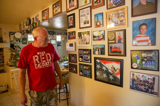 Mark Goldstrom, father to three adopted sons, reminisces as he looks upon various family photos he has displayed on a wall in his home, Friday June 6, 2018.