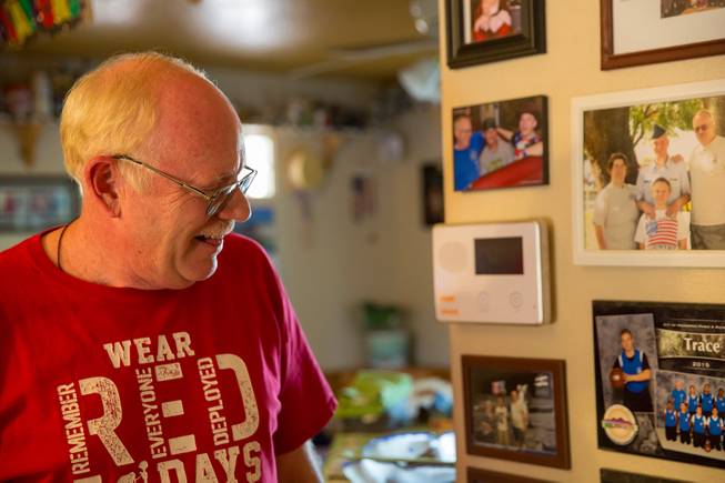 Mark Goldstrom, father to three adopted sons, reminisces as he looks upon various family photos he has displayed on a wall in his home, Friday June 6, 2018.