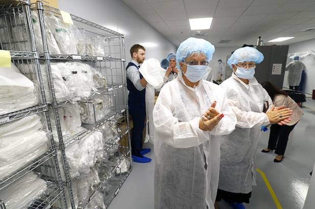 Guests suit up for a tour during the grand opening of Oasis Biotech, an indoor microgreen and herb vertical farming facility, Wednesday, July 18, 2018.