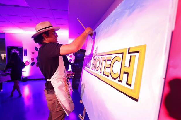 Artist Jeremiah Orfin works on a piece during the grand opening of Oasis Biotech, an indoor microgreen and herb vertical farming facility, Wednesday, July 18, 2018.
