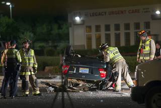 Henderson firefighters look over a Mazda Protege sedan after a fatal accident on Pecos Road at Wigwam Parkway in Henderson Aug. 23, 2018. One person died after the car hit a street light pole and rolled over.
