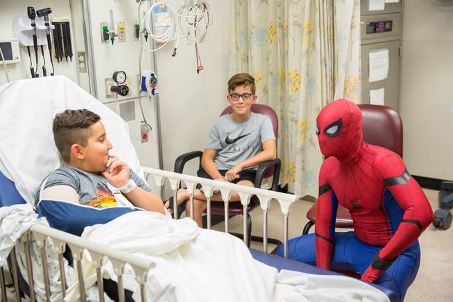 Critical Care Comics' Michael Mutzhause, as Spider-Man, visits with 9-year-old Sami, who is recovering from an elbow injury. He and other friendly superheroes are delivering comic books and toys to kids at UMC's Children's Hospital, Sat Aug. 18, 2018.