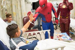Critical Care Comics' Michael Mutzhause, as Spiderman, gives a high-five to Sami, 9, as he and other friendly superheroes deliver comic books and toys to kids at UMC's Children's Hospital, Saturday, Aug. 18, 2018.