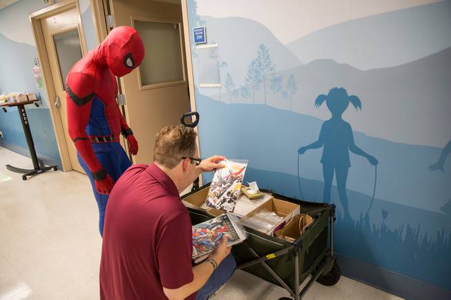 Jason Golden, founder and president of Critical Care Comics, thumbs through various comics as Michael Mutzhause, Spider-Man, prepares to deliver them to a sick child at UMC's Children's Hospital, Sat Aug. 18, 2018.