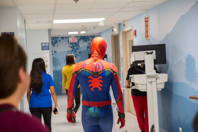Critical Care Comics' Michael Mutzhause, as Spider-Man, walks dowm a hopital corridor as he and other friendly superheroes deliver comic books and toys to kids at UMC's Children's Hospital, Sat Aug. 18, 2018.