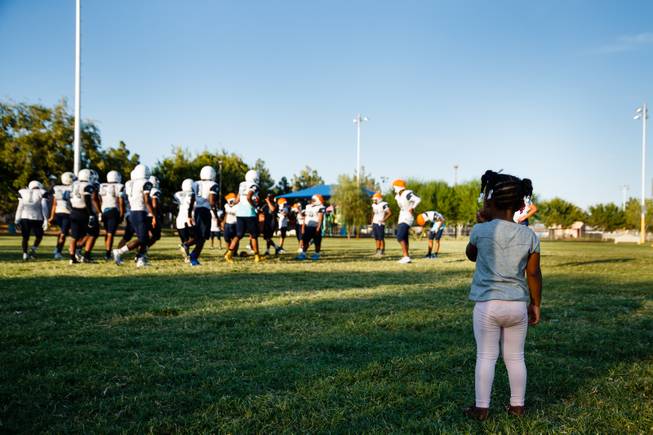 A little girl watches football players from Democracy Prep Academy practice at Kianga Isoke Palacio Park, Tuesday, Aug. 28, 2018. Practice is conducted at the nearby park because the school doesn't have its own field.