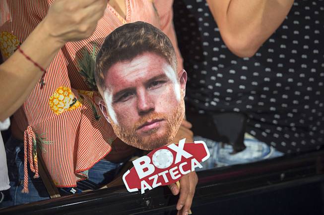 A boxing fan holds a photo of middleweight boxer Canelo Alvarez of Mexico as she waits for boxers to make their arrivals the MGM Grand hotel-casino in Las Vegas, Nev. Tuesday, Sept. 11, 2018.