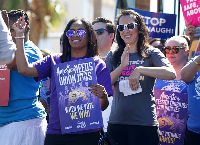 Regina Toney, left, a communications specialist with the SEIU Union, and Lindsey Harmon, executive director for  Nevada Advocates For Planned Parenthood Affiliates, cheer during a "Hop on the Progress Bus" news conference on West Sahara Avenue Wednesday, Sept. 19, 2018. A coalition of progressive groups joined to hold the news conference a day before President Trump's visit to Las Vegas.
