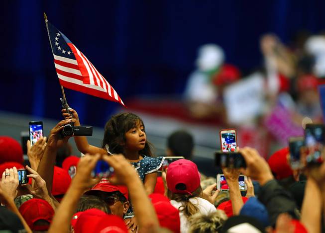 A girl waves a flag as President Donald Trump arrives for  a "Make America Great Again (MAGA) rally at the Las Vegas Convention Center Thursday, Sept. 20, 2018.