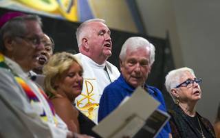 Father Bob Stoeckig, center, is joined by religious leaders on the Altar as they sing 'let There Be Peace on Earth