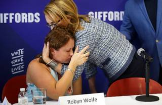 Robyn Wolfe, an Oct. 1 shooting survivor whose husband Bill Wolfe Jr. was killed, is embraced by former Arizona Congresswoman Gabrielle 