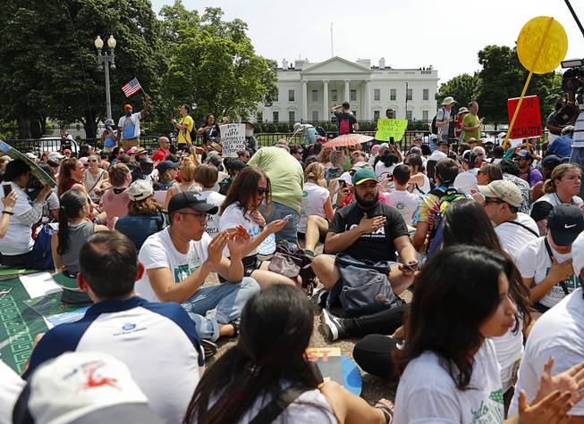 In this April 29, 2017, file photo, demonstrators sit on the ground along Pennsylvania Ave. in front of the White House in Washington. The National Park Service is exploring the question of whether it should recoup from protest organizers the cost of providing law enforcement and other support services for demonstrations held in the nation's capital. The proposed rule also could place new limits on spontaneous demonstrations and shrink a significant portion of the White House sidewalk accessible to the public. 