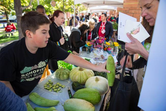 A student from Schofield Middle School sells a serpent melon to a woman during the Biannual Student Farmers Market at the Clark County Government Center, where students sell fruits and vegitables that are grown in school gardens, Thursday Nov. 8, 2018.
