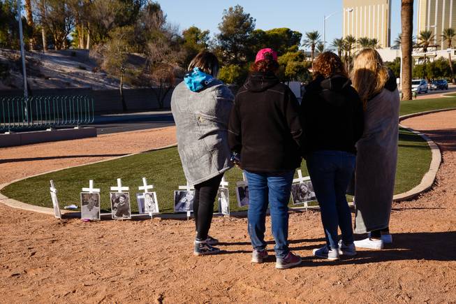 People look at memorial crosses for victims of the Thousand Oaks shooting massacre are seen near the Welcome to Fabulous Las Vegas sign, Monday, Nov. 12, 2018. Twelve people were killed when a gunman opened fire at a bar in Thousand Oaks, California.
