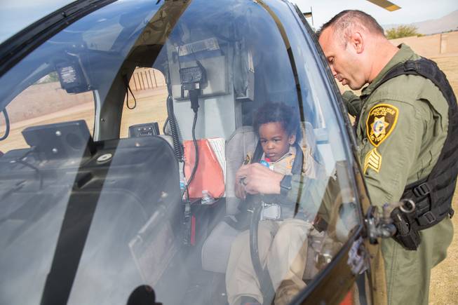 4-year-old Jon'tel Thomas sits in the pilot's seat of an LVMPD helicopter while Sgt. Dave Callen explains how the controls and instruments work, Friday Nov. 16, 2018.