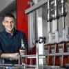 Jeff Tomastik, president of Derby Spirits/Ambros Banana Whiskey, poses by a bottling machine in the company's production facility in Henderson.