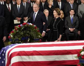 Former President George W. Bush and former first lady Laura Bush walk past the flag draped casket of former President George H.W. Bush in the Capitol Rotunda, Monday, Dec. 3, 2018 in Washington. (AP Photo/Pablo Martinez Monsivais/Pool)