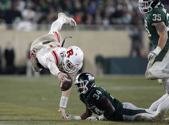 Rutgers quarterback Giovanni Rescigno, left, dives over Michigan State's Antjuan Simmons (34) as Joe Bachie (35) moves in during the fourth quarter of their game Saturday, Nov. 24, 2018, in East Lansing, Mich. Michigan State won 14-10. 