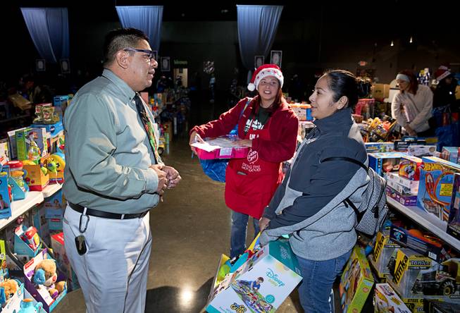 Juan Salinas, left, Salvation Army's director of social services, talks with Yeni Salinas-Salmeron (no relation) during the Salvation Army's Christmas Angel program at the Silver Nugget Events Center in North Las Vegas Friday, Dec. 14, 2018. Volunteer Annette Salazar looks at at center.