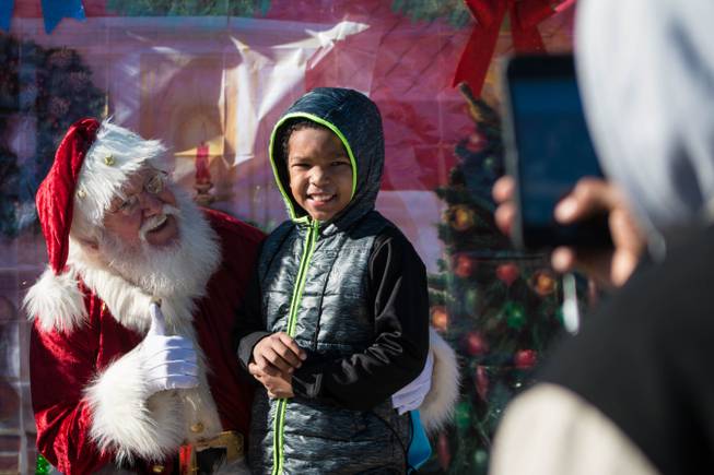 A boy poses for a photo with an actor dressed as Santa Claus at the Boys & Girls Club, 920 Cottage Grove Ave. This Dec. 15, 2018, event provided gifts, games and food for dozens of neighborhood children and their families. 
