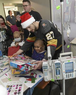 Vegas Golden Knights defenseman Shea Theodore gives presents to a young patient during a visit to Summerlin Hospital Friday, December 21, 2018.