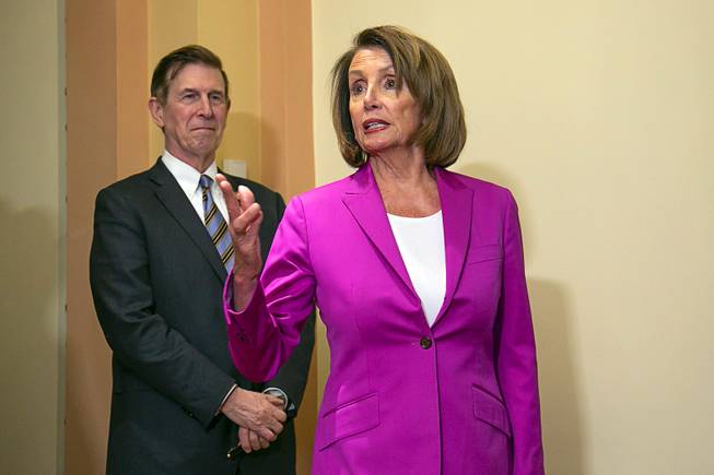 Speaker of the House Nancy Pelosi, D-Calif., joined at left by Rep. Don Beyer D-Va., talks to reporters after signing a House-passed a bill requiring that all government workers receive retroactive pay after the partial shutdown ends, at the Capitol in Washington, Friday, Jan. 11, 2019. 